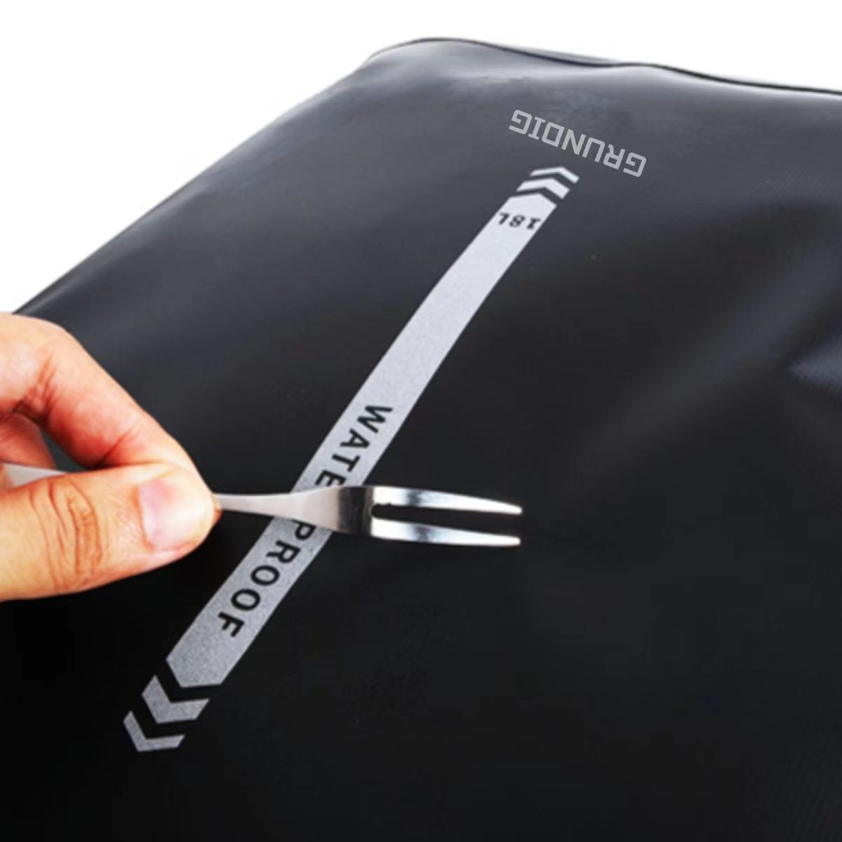 Scratch resistance test on Grundig 2.5L waterproof pannier bag – fork scraping surface to demonstrate durability